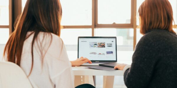 two women talking while looking at laptop computer